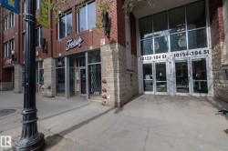 Brick and stone facade building featuring prominent street-level retail space with large display windows, a contemporary glass entryway, and visible street numbers - 