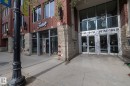 Brick and stone facade building featuring prominent street-level retail space with large display windows, a contemporary glass entryway, and visible street numbers - 3104 10152 104 Street, Edmonton, AB  - Outdoor 