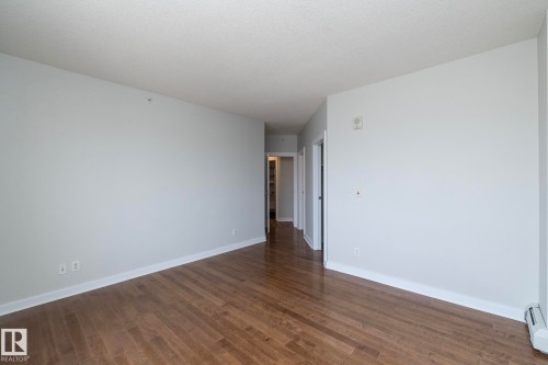 Spacious room featuring wood-finish flooring, light grey walls, white baseboards, and a textured white ceiling - 3104 10152 104 Street, Edmonton, AB - Indoor Photo Showing Other Room