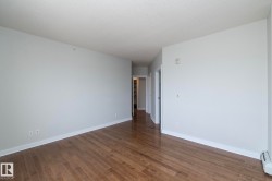 Spacious room featuring wood-finish flooring, light grey walls, white baseboards, and a textured white ceiling - 