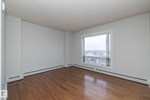 Expansive room featuring wood-finish flooring, a large window, a neutral color palette, and baseboard heating - 3104 10152 104 Street, Edmonton, AB - Indoor Photo Showing Other Room