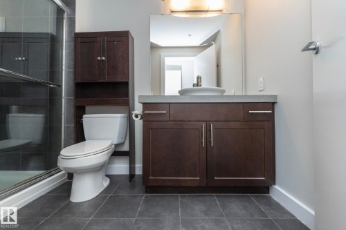 Bathroom featuring dark wood-finish vanity with a vessel sink, a full-width mirror, and a built-in shower with sliding glass doors - 3104 10152 104 Street, Edmonton, AB - Indoor Photo Showing Bathroom