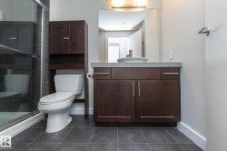 Bathroom featuring dark wood-finish vanity with a vessel sink, a full-width mirror, and a built-in shower with sliding glass doors - 