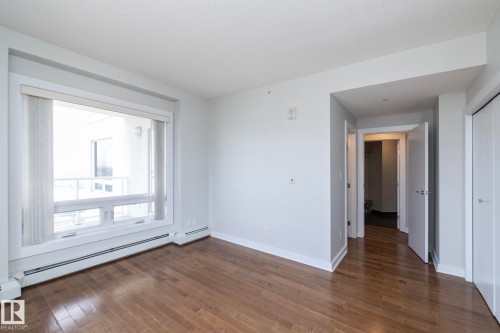 Bright living area featuring wood-finish flooring and a large window with vertical blinds - 3104 10152 104 Street, Edmonton, AB - Indoor Photo Showing Other Room