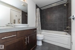 Bathroom featuring a dark wood-finish vanity with a vessel sink and brushed nickel fixtures - 