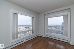 Expansive windows provide far-reaching urban panoramas, complemented by wood-finish flooring, white trim, and light gray wall finishes - 