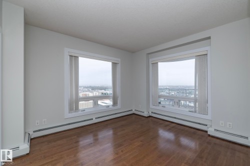 Expansive windows offering urban scenery complement wood-finish flooring in this bright interior - 3104 10152 104 Street, Edmonton, AB - Indoor Photo Showing Other Room