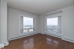 Expansive windows offering urban scenery complement wood-finish flooring in this bright interior - 