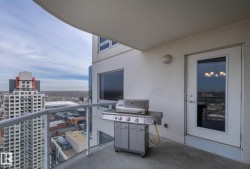 Private balcony featuring a gas-fed grill, glass panel railing, and cityscape backdrop - 