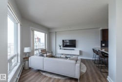 Open-concept living area featuring extensive window panels, wood-finish flooring, and a breakfast bar with seating - 
