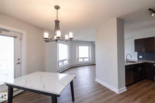 Open-concept living space featuring wood-finish flooring, a contemporary chandelier, and large windows - 3104 10152 104 Street, Edmonton, AB - Indoor Photo Showing Other Room
