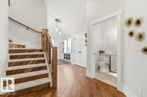 Hardwood flooring extends throughout the entry, complemented by a wood and metal staircase with carpeted treads - 1 Sparrow Close, Fort Saskatchewan, AB - Indoor Photo Showing Other Room