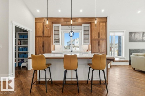 Gourmet kitchen with wood-finish flooring, a white island, and integrated wood cabinetry - 1 Sparrow Close, Fort Saskatchewan, AB - Indoor