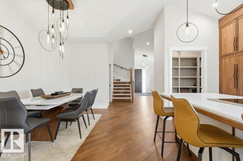 Open-concept living space featuring herringbone wood-finish flooring, a contemporary dining chandelier, recessed lighting, and a white vaulted ceiling - 1 Sparrow Close, Fort Saskatchewan, AB - Indoor Photo Showing Dining Room