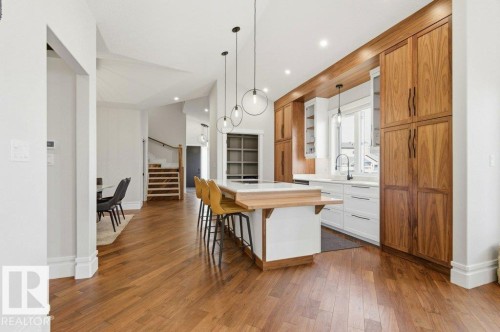 Gourmet kitchen featuring a central island with a wood-finish countertop, full-height wood-finish cabinetry, white shaker-style base cabinetry, integrated lighting, and wood-finish flooring - 1 Sparrow Close, Fort Saskatchewan, AB - Indoor