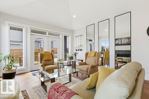 Spacious living area featuring wood-finish flooring, a vaulted ceiling, and multiple full-length mirrors - 1 Sparrow Close, Fort Saskatchewan, AB - Indoor Photo Showing Living Room