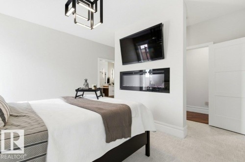 Recessed electric fireplace and a modern geometric ceiling light fixture - 1 Sparrow Close, Fort Saskatchewan, AB - Indoor Photo Showing Bedroom With Fireplace