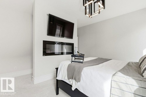 Integrated wall-mounted fireplace with a television installation - 1 Sparrow Close, Fort Saskatchewan, AB - Indoor Photo Showing Bedroom