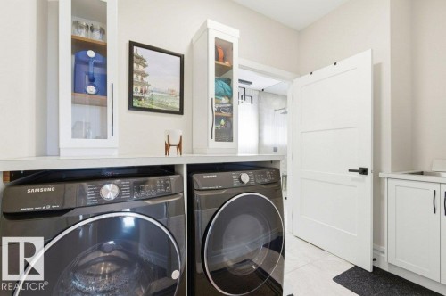 Laundry area featuring front-loading machines, white cabinetry, and a utility sink - 1 Sparrow Close, Fort Saskatchewan, AB - Indoor Photo Showing Laundry Room
