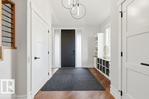 Spacious entryway featuring rich wood-finish flooring, a contemporary black front door with sidelights, and a modern ceiling light fixture - 1 Sparrow Close, Fort Saskatchewan, AB - Indoor Photo Showing Other Room