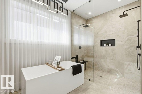 Contemporary bathroom featuring a freestanding soaking tub, a spacious glass-enclosed shower with dual showerheads, and large-format wall tiling - 1 Sparrow Close, Fort Saskatchewan, AB - Indoor Photo Showing Bathroom