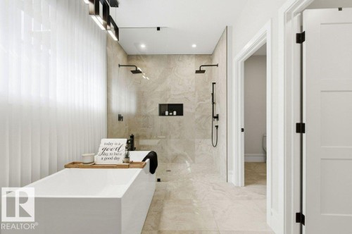 Freestanding soaking tub with a spacious walk-in shower featuring dual showerheads, a wall-mounted handheld sprayer, and tiled walls with a recessed niche - 1 Sparrow Close, Fort Saskatchewan, AB - Indoor Photo Showing Other Room