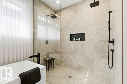 Contemporary bathroom featuring a freestanding soaking tub with matte black fixtures, a walk-in shower with a rain showerhead and handheld shower, large format tile walls, and a recessed shower niche - 1 Sparrow Close, Fort Saskatchewan, AB - Indoor Photo Showing Bathroom