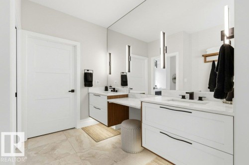 Spacious bathroom featuring dual vanities with white cabinetry, light stone countertops, and integrated sinks - 1 Sparrow Close, Fort Saskatchewan, AB - Indoor Photo Showing Bathroom