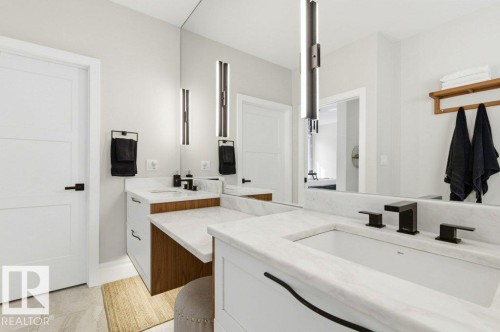 Contemporary bathroom featuring a dual vanity with white countertops, integrated sinks, and matte black fixtures - 1 Sparrow Close, Fort Saskatchewan, AB - Indoor Photo Showing Bathroom