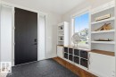 Entryway featuring a large black door with frosted sidelights, built-in shelving, integrated lower cabinetry, wood-finish flooring, and a large window - 1 Sparrow Close, Fort Saskatchewan, AB  - Indoor Photo Showing Other Room 