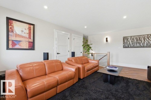 Brightly lit interior space featuring recessed ceiling lighting, a contemporary wood and metal railing, and white interior doors with black hardware - 1 Sparrow Close, Fort Saskatchewan, AB - Indoor Photo Showing Living Room