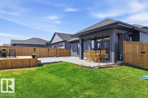 Expansive backyard featuring a large green lawn, concrete patio, and a raised wooden deck - 1 Sparrow Close, Fort Saskatchewan, AB - Outdoor With Deck Patio Veranda