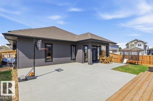 Expansive concrete patio with covered outdoor dining area, horizontal siding exterior, and shingled roof - 1 Sparrow Close, Fort Saskatchewan, AB - Outdoor With Deck Patio Veranda