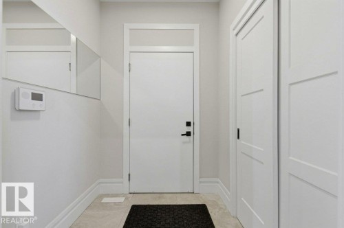 Front entry featuring a solid core door with transom window, modern black hardware, three-panel interior doors, and light-toned tile flooring - 1 Sparrow Close, Fort Saskatchewan, AB - Indoor Photo Showing Other Room