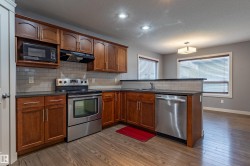 Kitchen featuring wood-finish flooring, cherry wood cabinetry, and stainless steel appliances - 