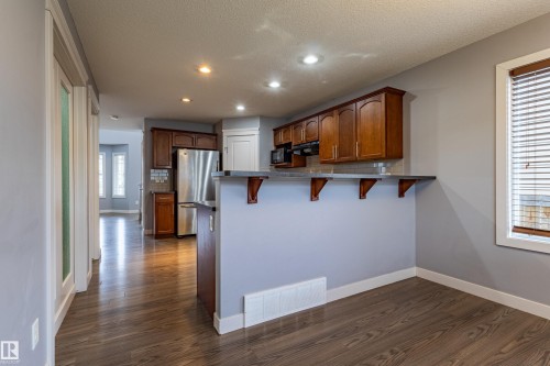 Kitchen featuring wood-finish flooring, recessed lighting, and a breakfast bar with decorative corbels - 17715 6 Avenue, Edmonton, AB - Indoor Photo Showing Kitchen