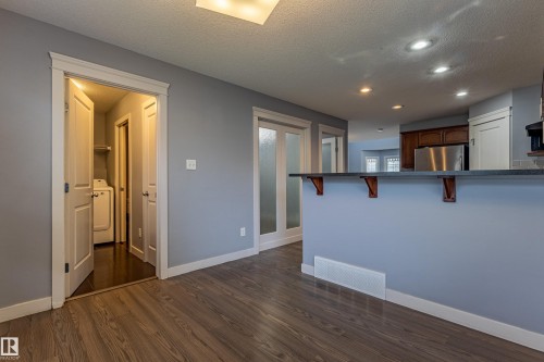 Wood-finish flooring throughout, featuring a kitchen island with dark countertop and decorative corbels - 17715 6 Avenue, Edmonton, AB - Indoor Photo Showing Kitchen