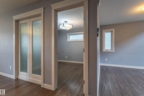Interior space featuring wood-finish flooring, light gray wall paint, and white trim - 17715 6 Avenue, Edmonton, AB - Indoor Photo Showing Other Room