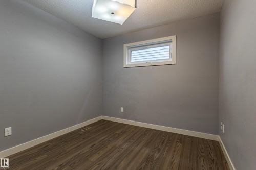 Neutral gray walls complement the wood-finish flooring - 17715 6 Avenue, Edmonton, AB - Indoor Photo Showing Other Room