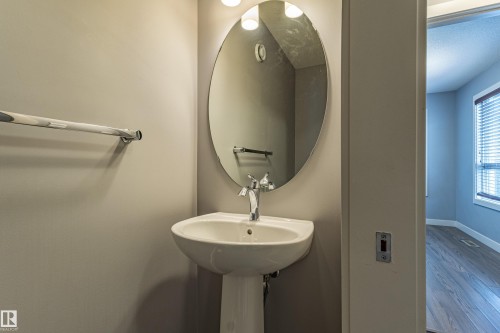 Pedestal sink with chrome faucet and oval mirror - 17715 6 Avenue, Edmonton, AB - Indoor Photo Showing Bathroom