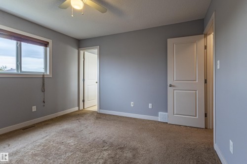 Carpeted room featuring a ceiling fan with integrated lighting, a double-pane window with wood-finish blinds, and two panel interior doors - 17715 6 Avenue, Edmonton, AB - Indoor Photo Showing Other Room