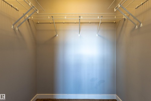 Wardrobe space featuring white wire shelving units, light grey wall paint, white baseboards, and brown carpet flooring - 17715 6 Avenue, Edmonton, AB - Indoor With Storage