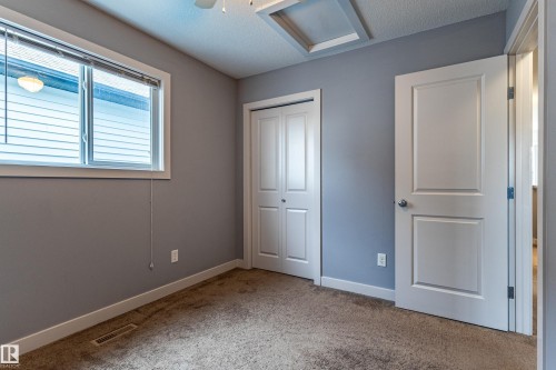 Spacious room featuring neutral carpeting, a large window with blinds, a bi-fold closet door, and a paneled interior door - 17715 6 Avenue, Edmonton, AB - Indoor Photo Showing Other Room