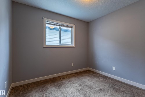 Light gray painted walls with white trim, brown carpeted flooring, and a single window with white blinds - 17715 6 Avenue, Edmonton, AB - Indoor Photo Showing Other Room