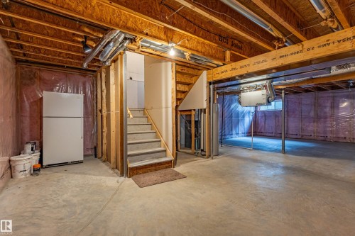 Unfinished basement featuring exposed wood joists, concrete flooring, and a carpeted staircase - 17715 6 Avenue, Edmonton, AB - Indoor Photo Showing Basement
