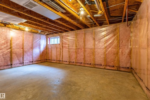 Unfinished basement space featuring exposed wooden joists, concrete flooring, insulated walls, an egress window, and visible HVAC ductwork - 17715 6 Avenue, Edmonton, AB - Indoor Photo Showing Basement