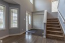 Entryway featuring wood-finish flooring, a carpeted staircase with white handrails, a front door with decorative glass inserts, and a coat closet with bi-fold doors - 17715 6 Avenue, Edmonton, AB  - Indoor Photo Showing Other Room 