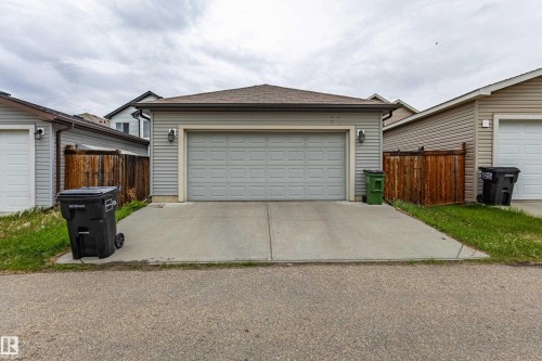 Rear-facing attached garage with a panel-style door and twin exterior wall sconces - 17715 6 Avenue, Edmonton, AB - Outdoor With Exterior