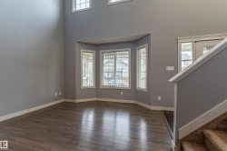 Open concept living area featuring dark wood-finish flooring and a bay window with multiple panes - 
