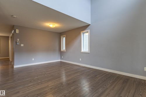 Interior space featuring wood-finish flooring, light grey painted walls, white baseboards, and white window trim - 17715 6 Avenue, Edmonton, AB - Indoor Photo Showing Other Room
